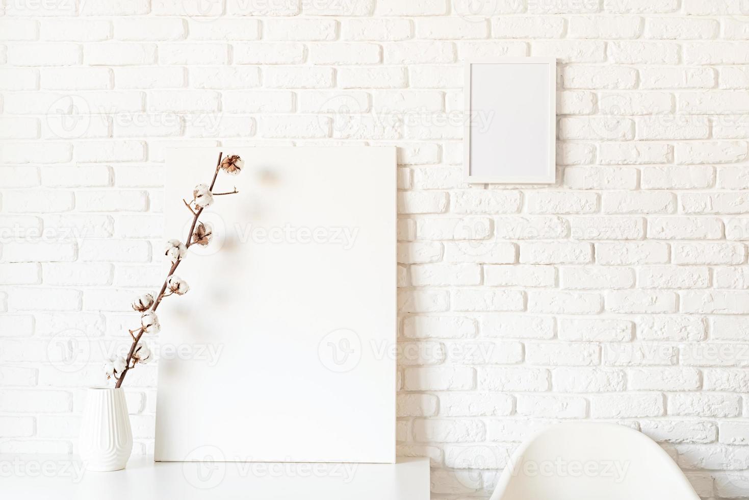 Mock up poster frame with cotton branch on white brick wall background photo