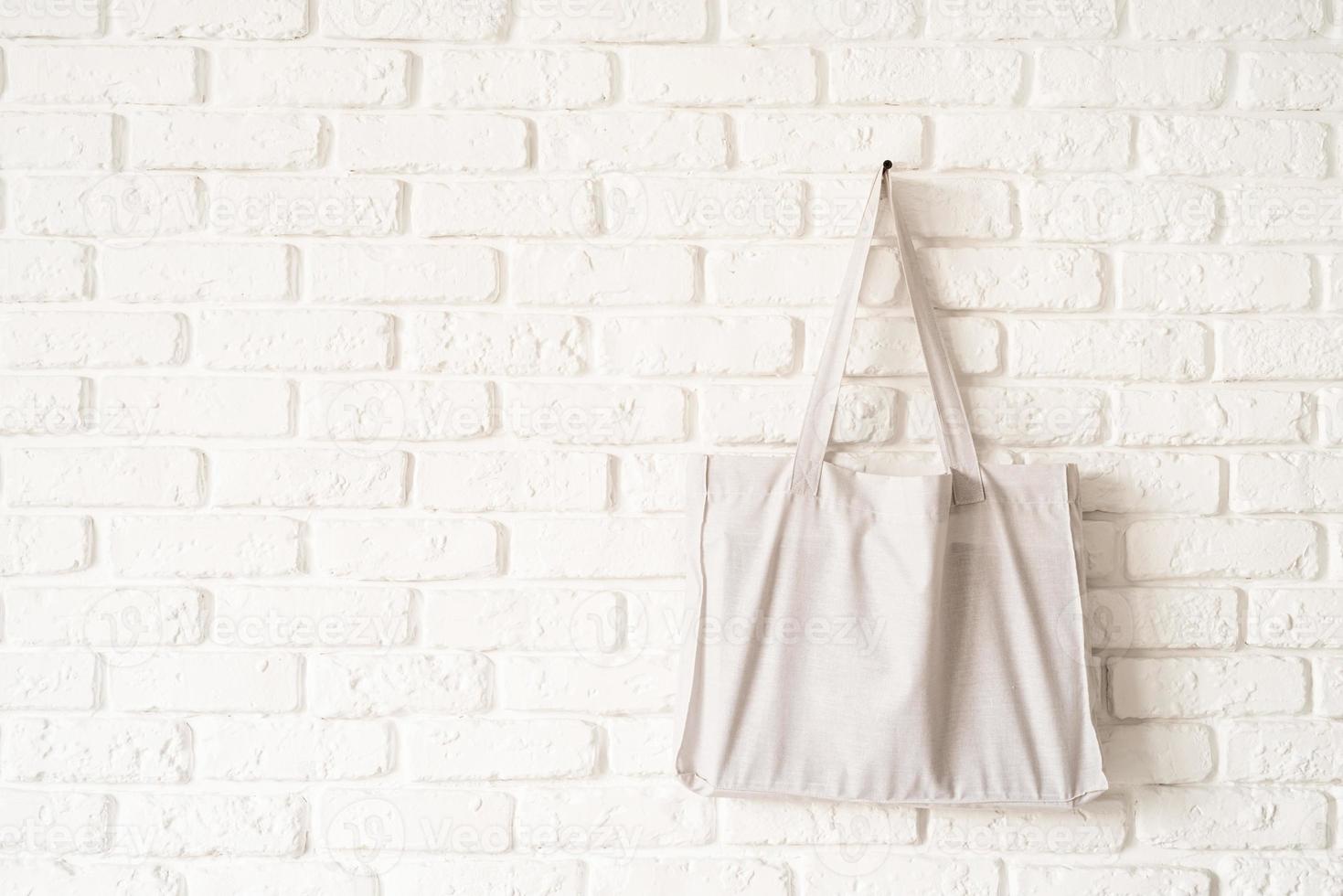 Mock up tote bag eco hipster white cotton fabric on white brick wall photo