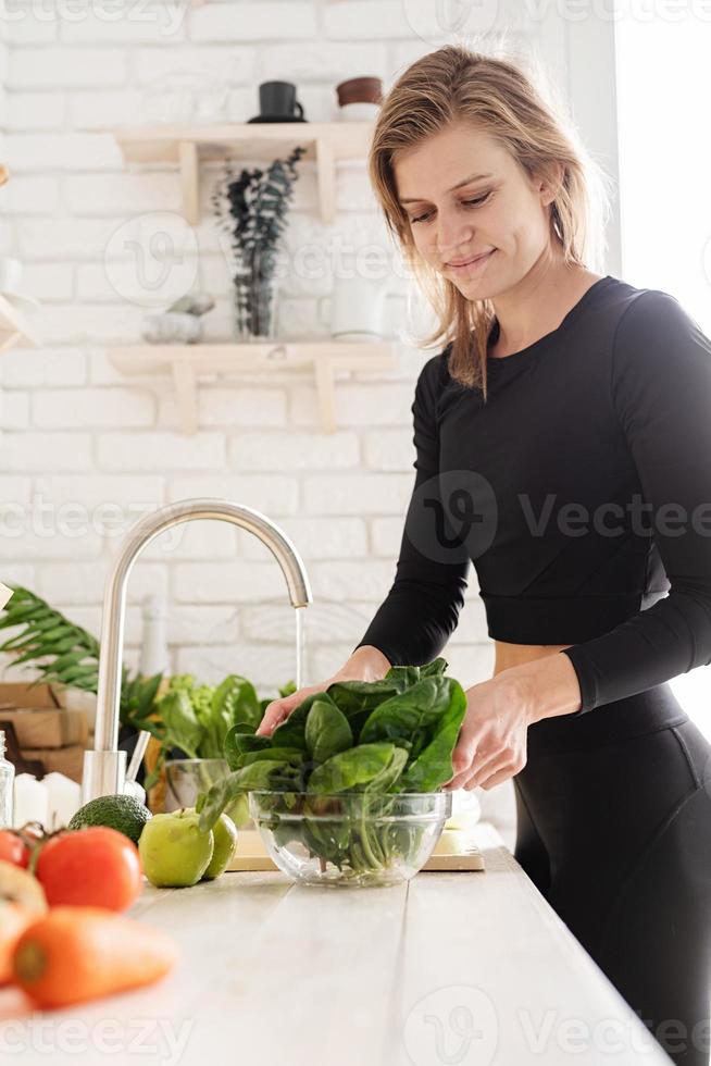 Mujer lavando apio en el fregadero de la cocina foto