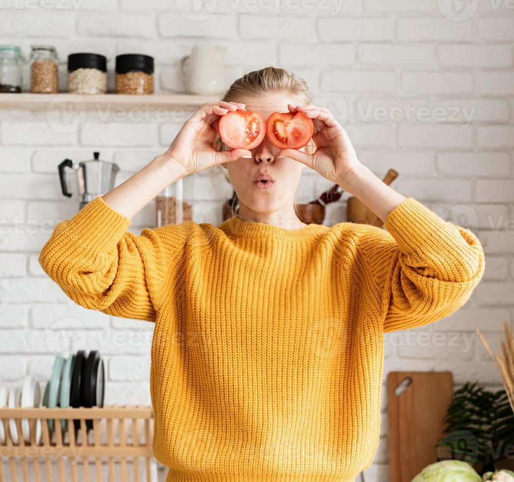 Funny woman playing with tomatoes, making salad in kitchen photo