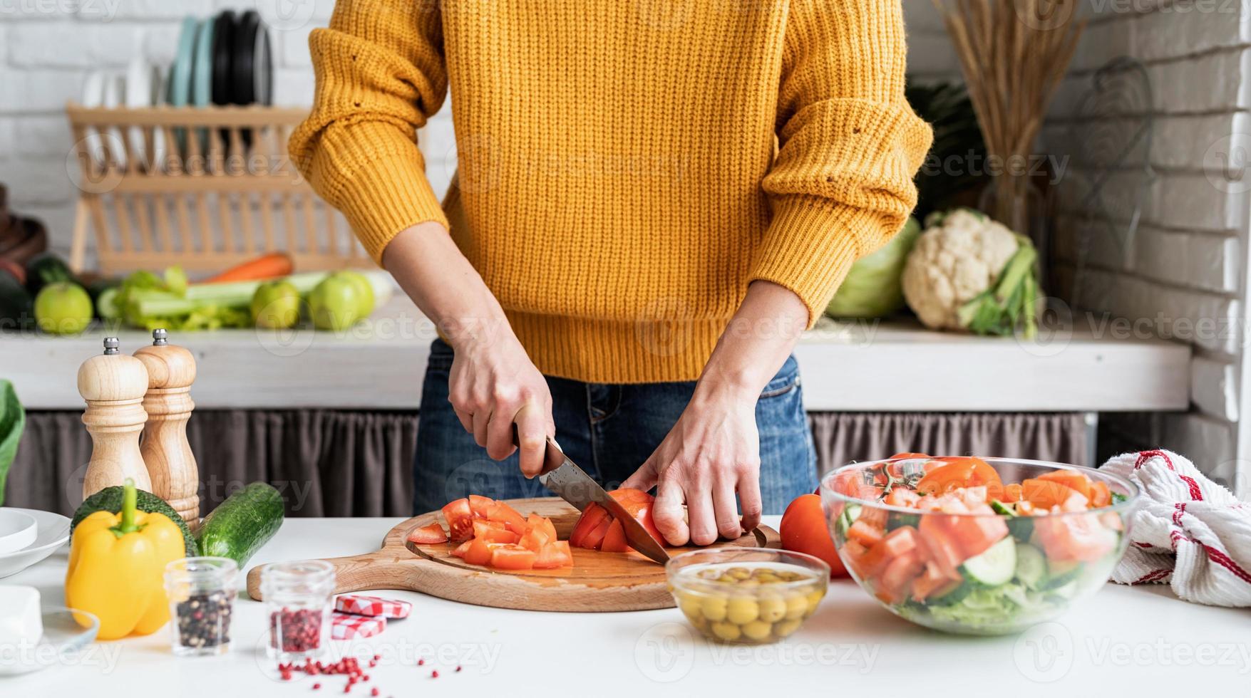 Female hands making salad cutting tomatoes in the kitchen photo