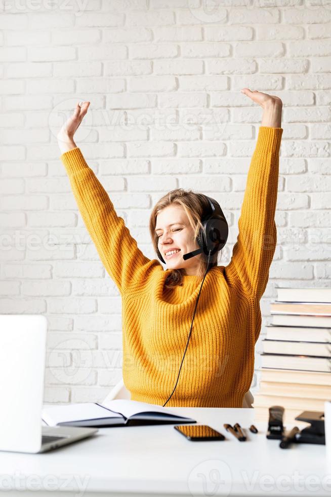 Woman sitting at the desk stretching after long study photo