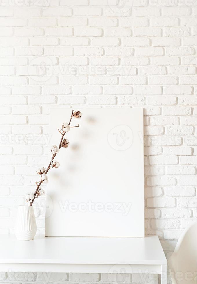 Mock up poster frame with cotton branch on white brick wall background photo