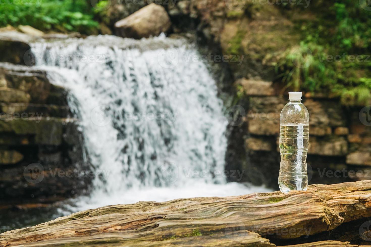 Botella de plástico transparente con agua en el fondo de la cascada foto