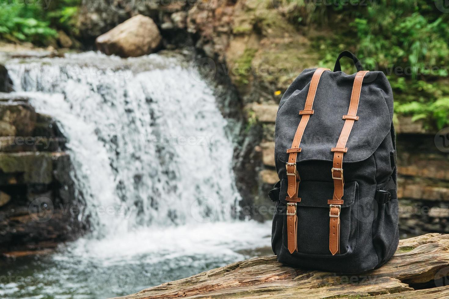 Hipster hiker tourist backpack on background of river and waterfall photo