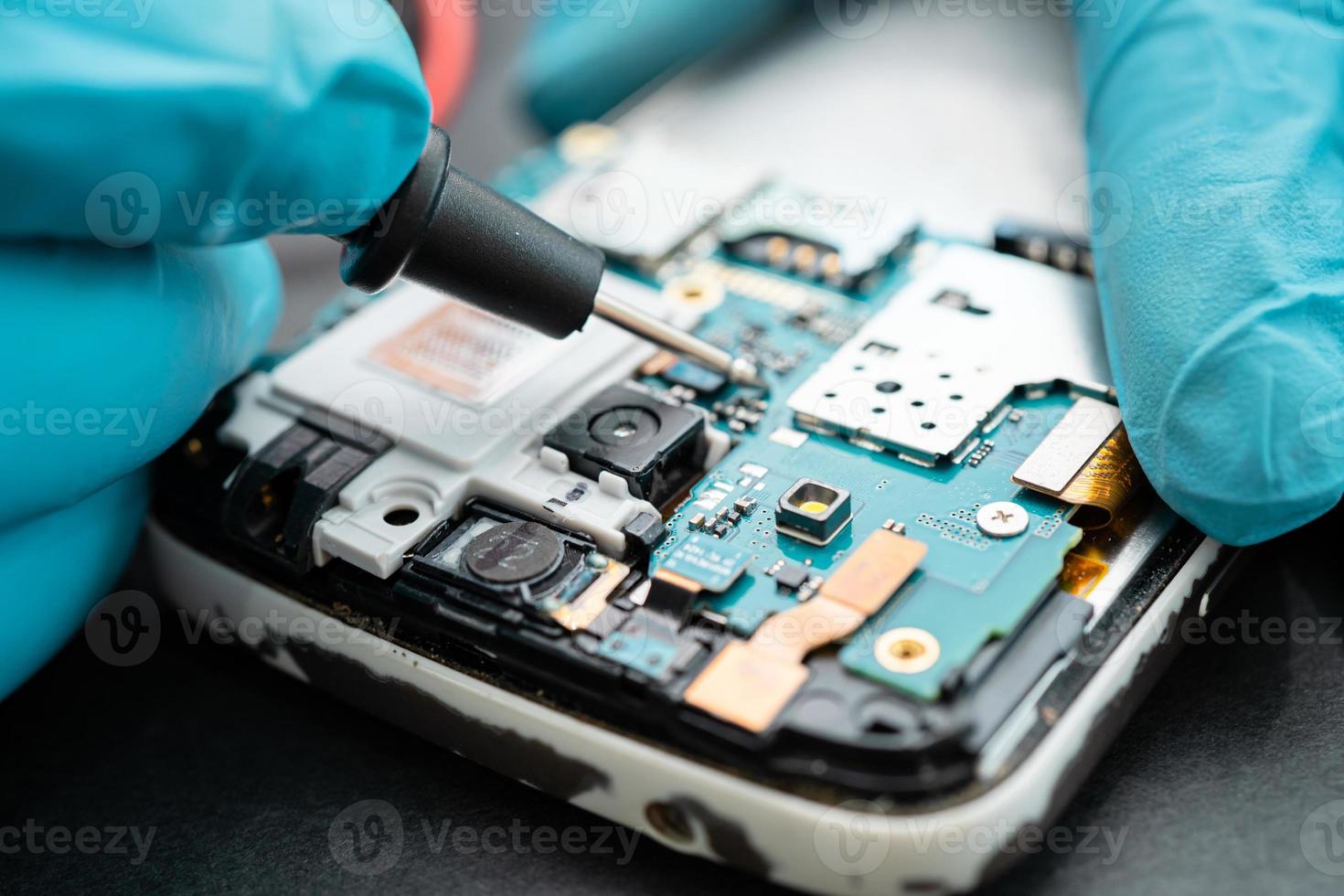 Technician repairing inside of mobile phone by soldering iron. photo