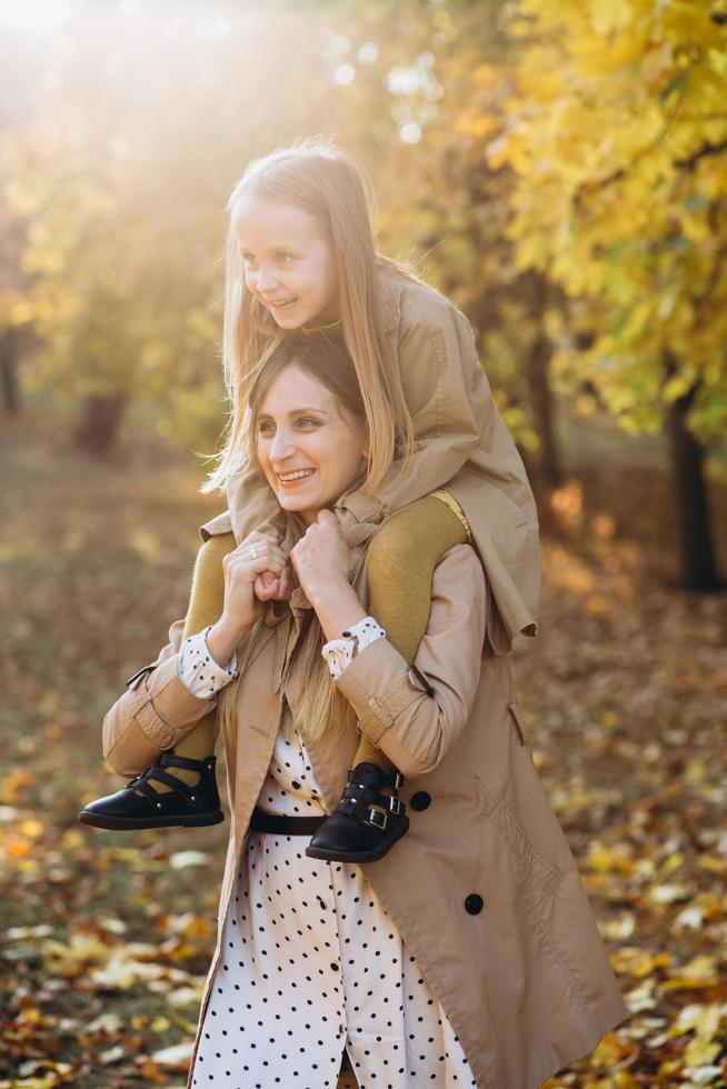 madre y su hija se divierten y caminan en el parque de otoño. foto