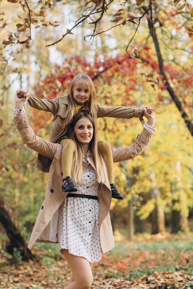 madre y su hija se divierten y caminan en el parque de otoño. foto