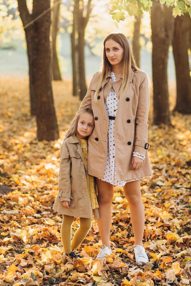 madre y su hija se divierten y caminan en el parque de otoño. foto