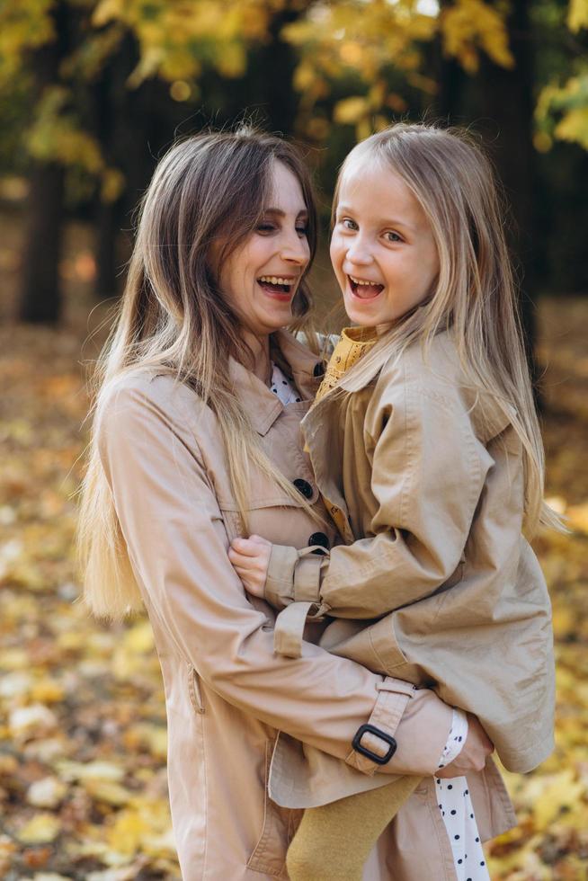 Mother and her daughter have fun and walk in the autumn park. photo