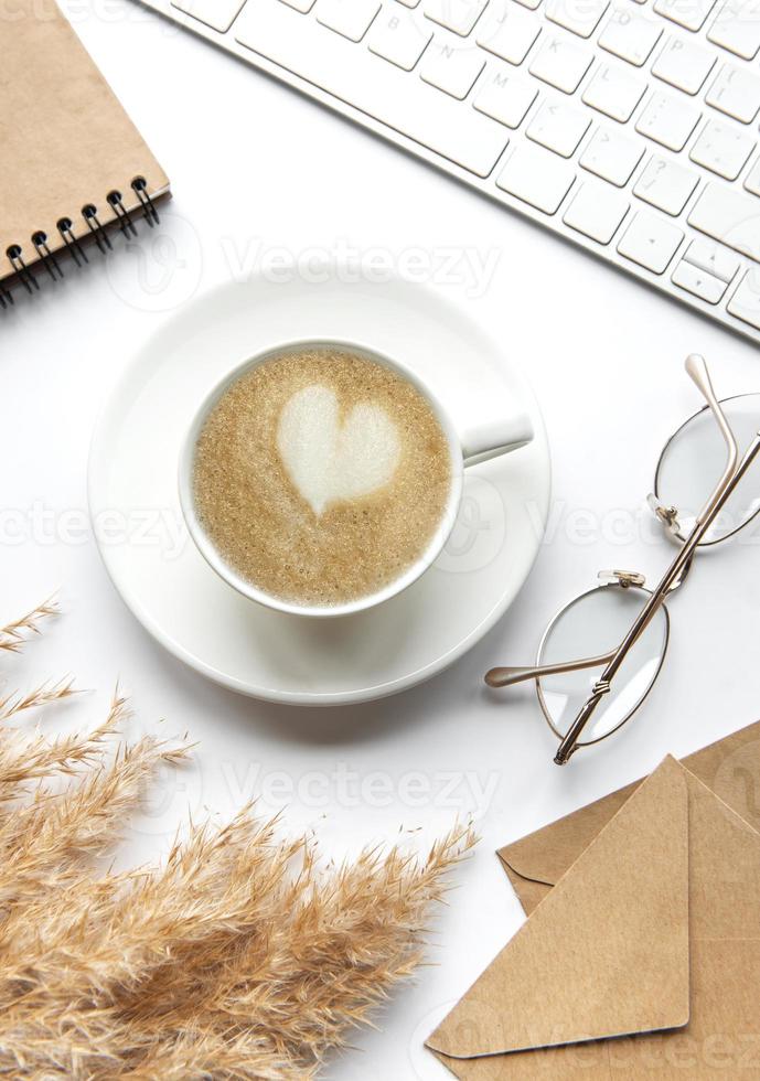 espacio de trabajo de escritorio de oficina con cuaderno, café y pasto de la pampa. foto