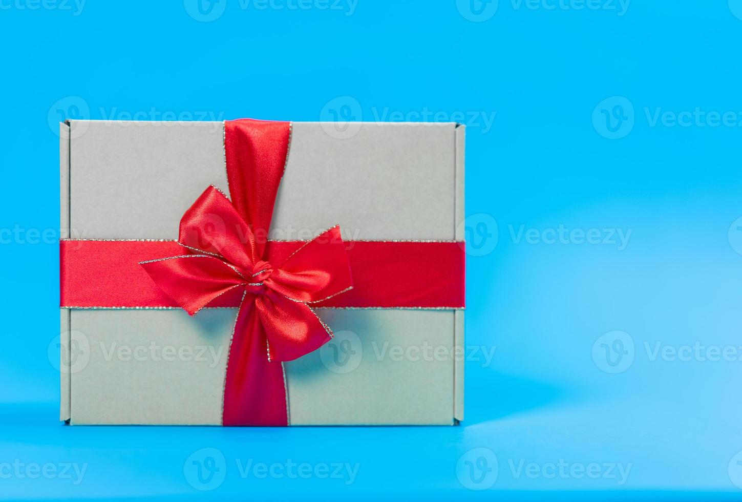 caja de regalo con cinta roja sobre fondo azul foto