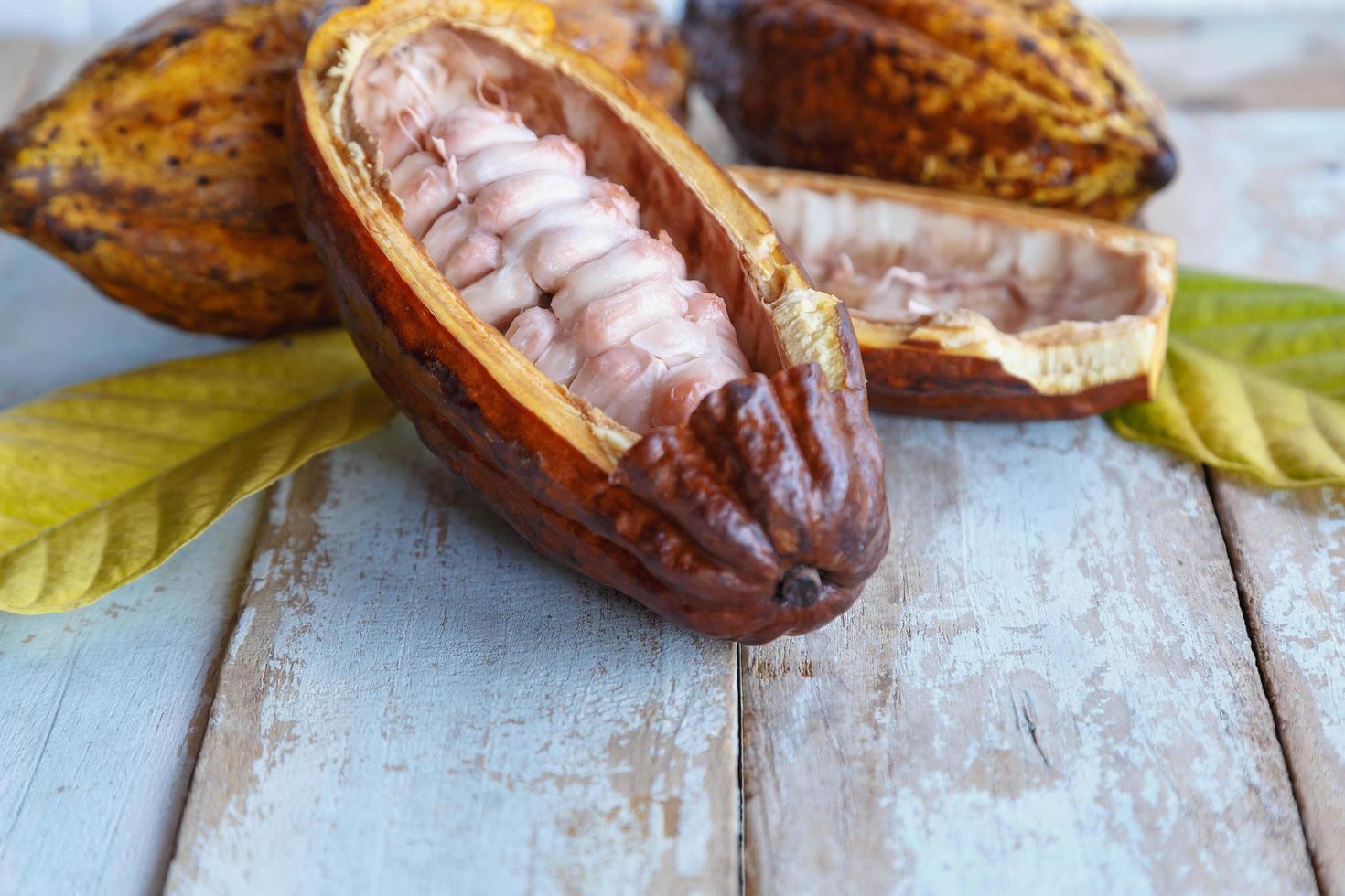 Fresh cocoa pods and cocoa leaves on wooden background photo