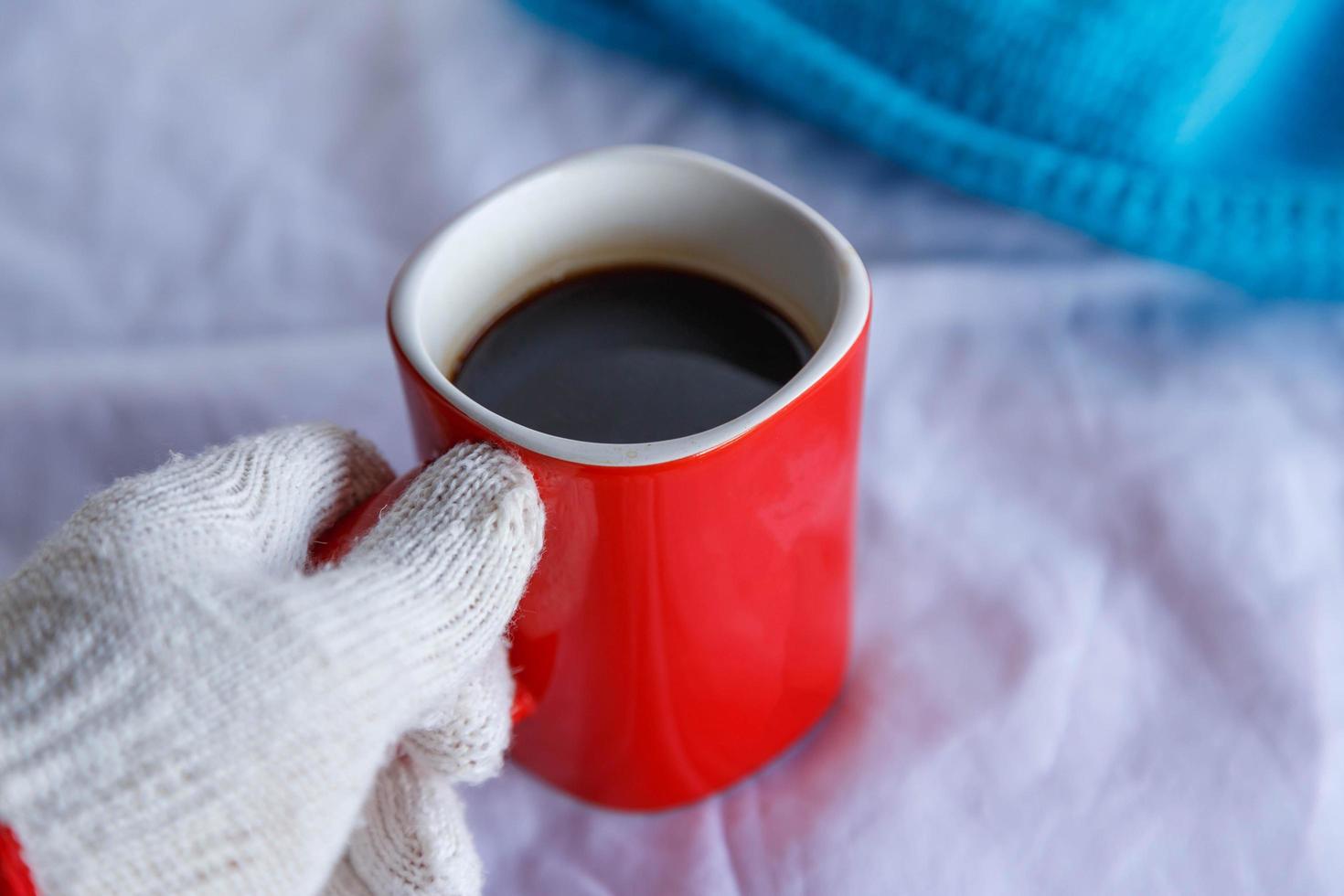 taza de café roja en la mano con guantes en invierno foto