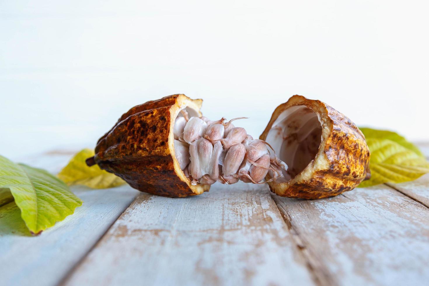 Fresh cocoa pods and cocoa leaves on wooden background photo