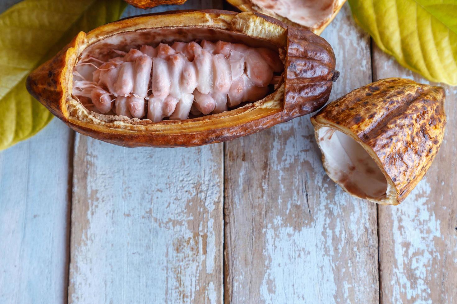Fresh cocoa pods and cocoa leaves on wooden background photo
