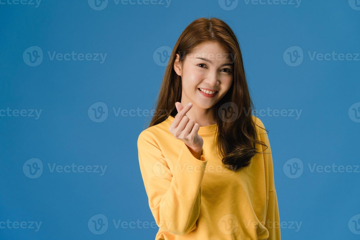 joven asiática muestra gesto de las manos en forma de corazón sobre fondo azul. foto