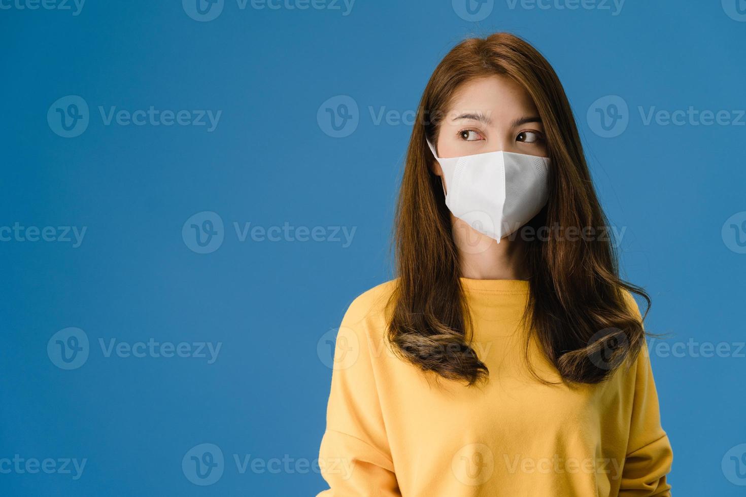 Young Asian girl wearing medical face mask on blue background. photo