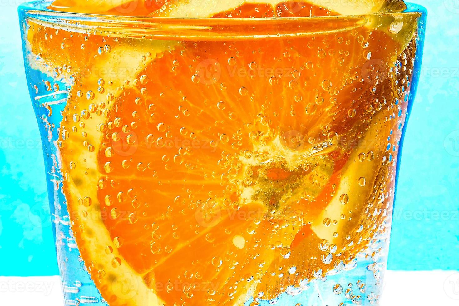 Close-up de una rodaja de naranja con burbujas en un vaso de agua con gas foto