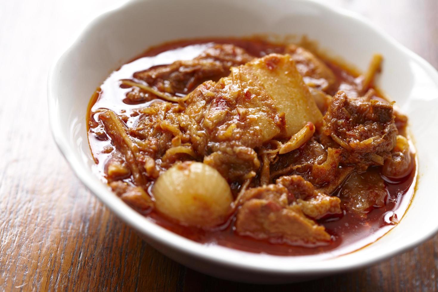 Red pork curry on wooden table photo