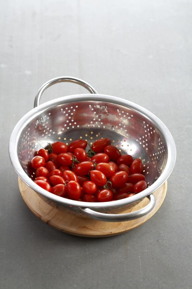 Muchos tomate en recipiente de metal sobre placa de madera foto