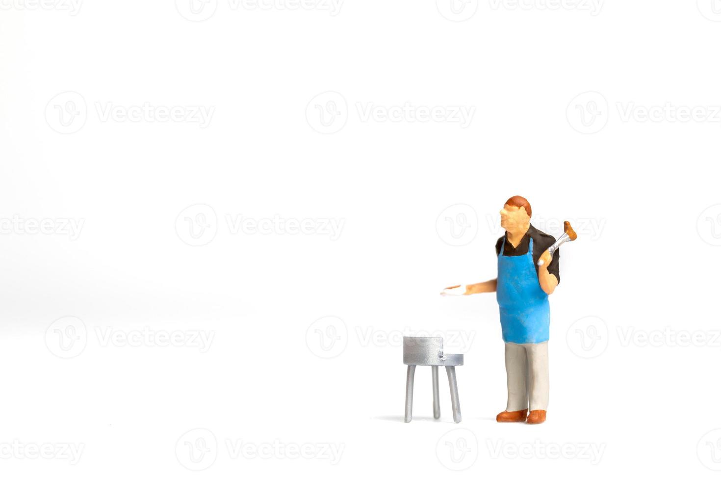 Miniature people, Chef cooking steak on barbecue grill  isolated on white background photo