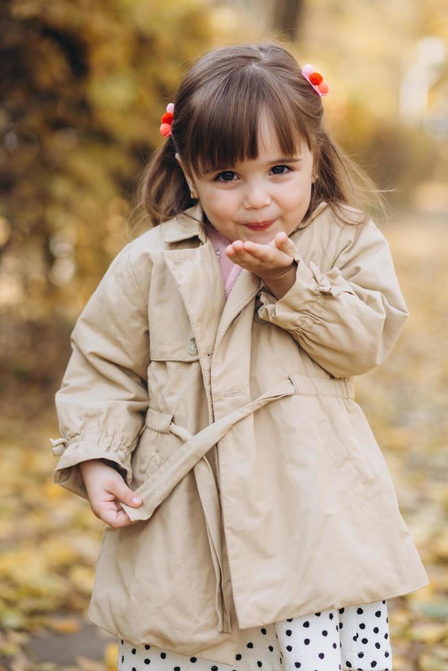 Beautiful little girl shows an air kiss in the autumn park photo