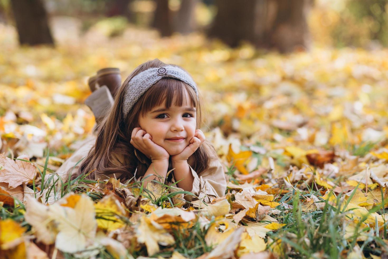 hermosa niña se encuentra entre las hojas amarillas en el parque de otoño foto