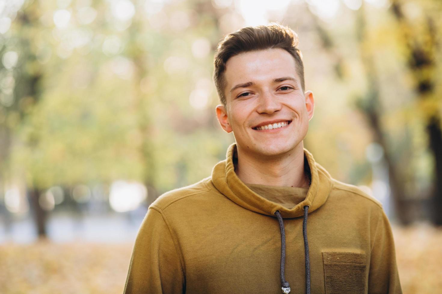 Portrait of handsome guy smiling in the autumn park photo