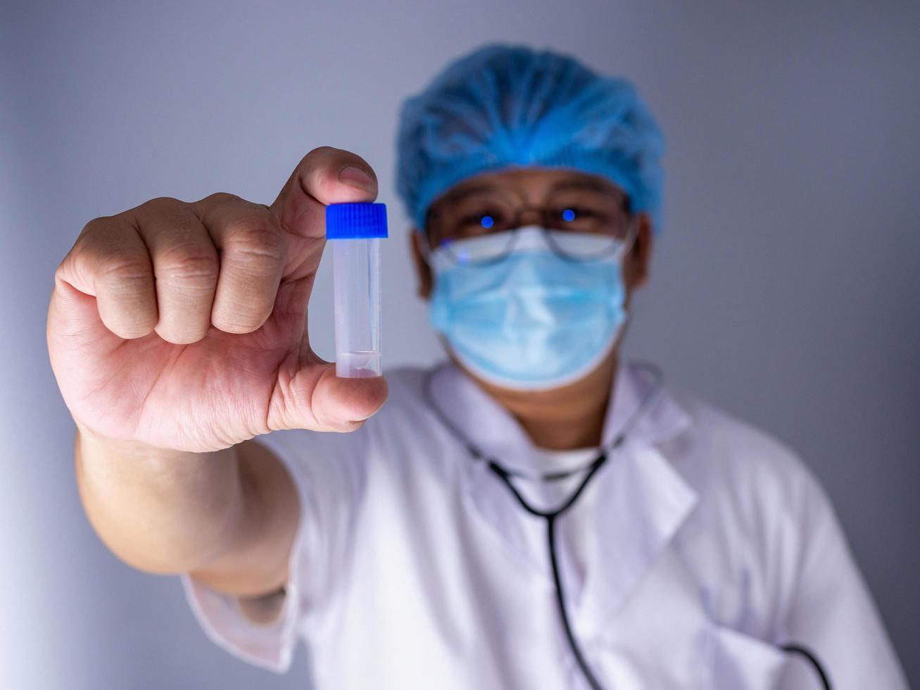 doctor sosteniendo una botella y usando una máscara foto