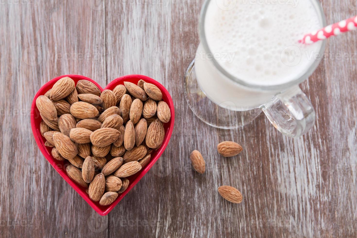 almendras en recipiente en forma de corazón con leche de almendras foto