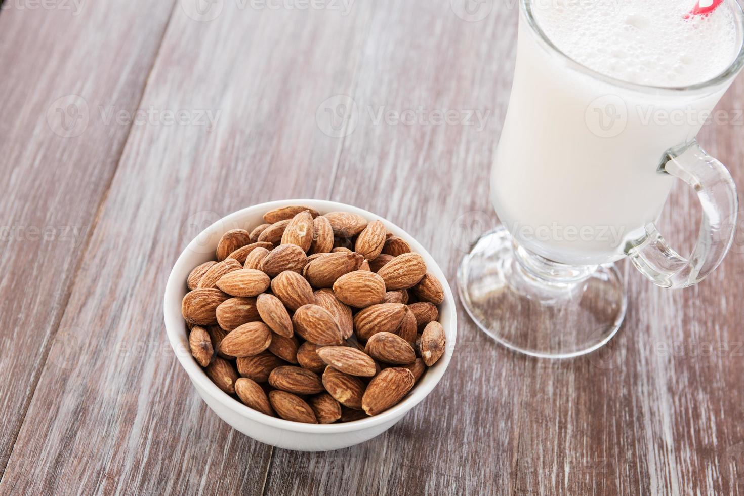 Cuenco de almendras sobre fondo de madera con leche foto