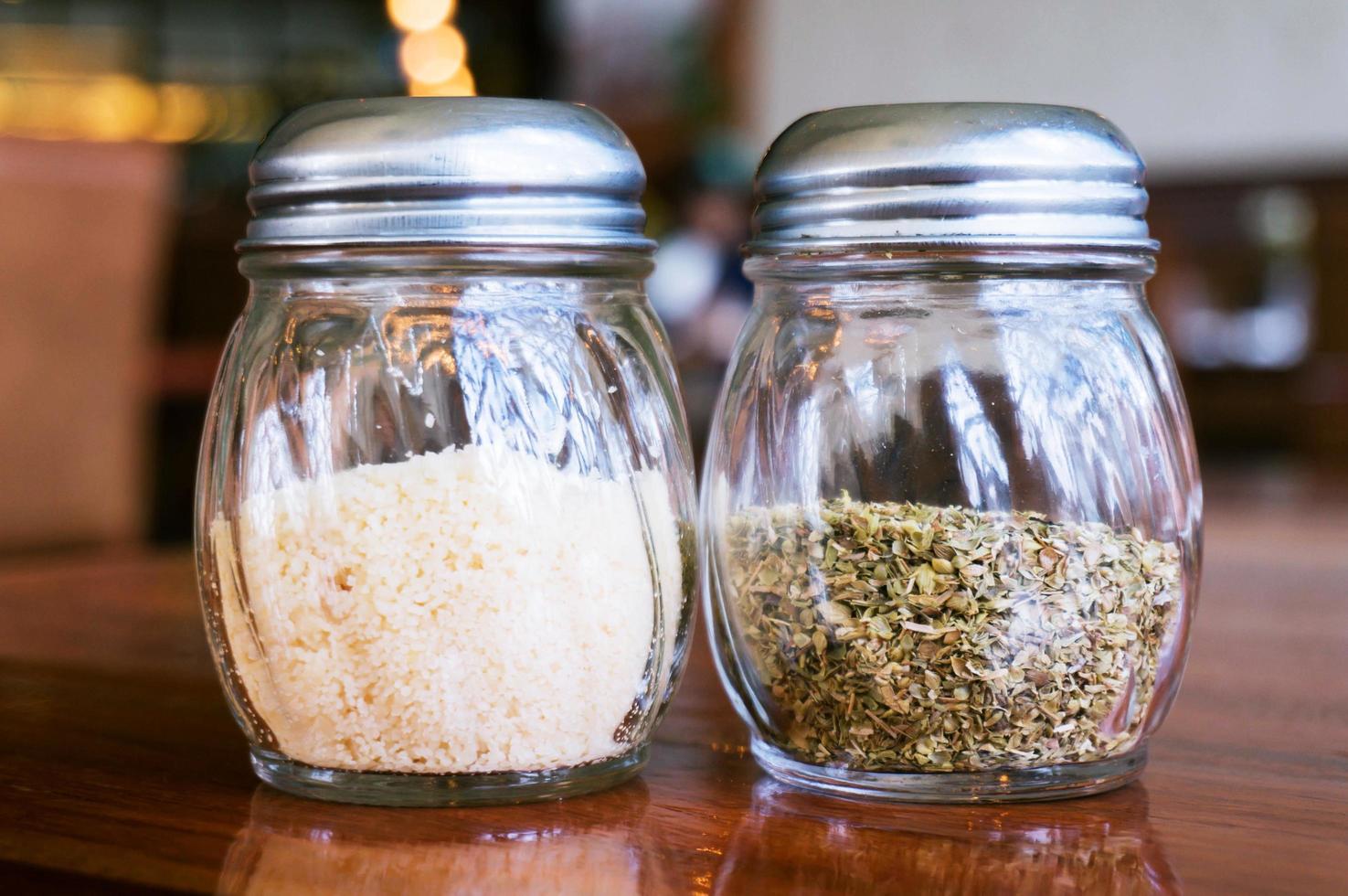 Glass of cheese salt and pepper shakers on wooden table in restaurant photo