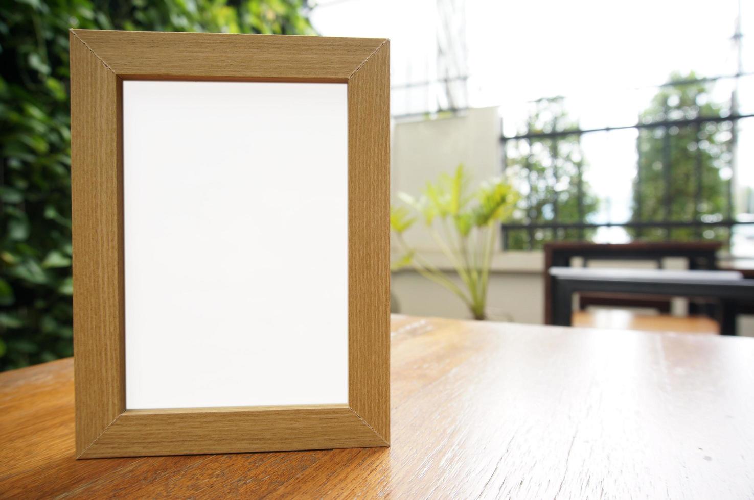 Simulacros de marco blanco en blanco de pie sobre la mesa de madera foto