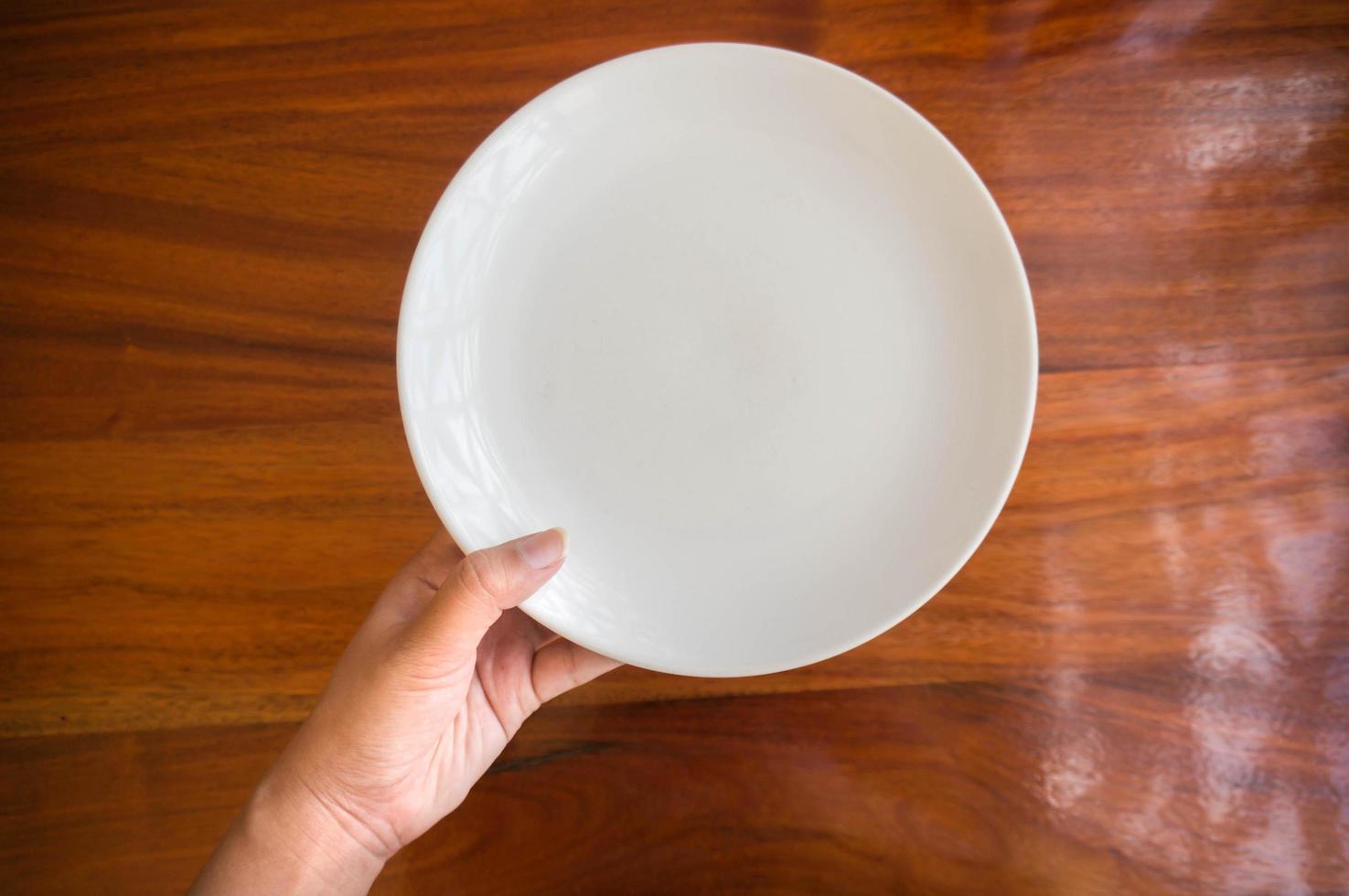 Female hands hold a white dish plate photo