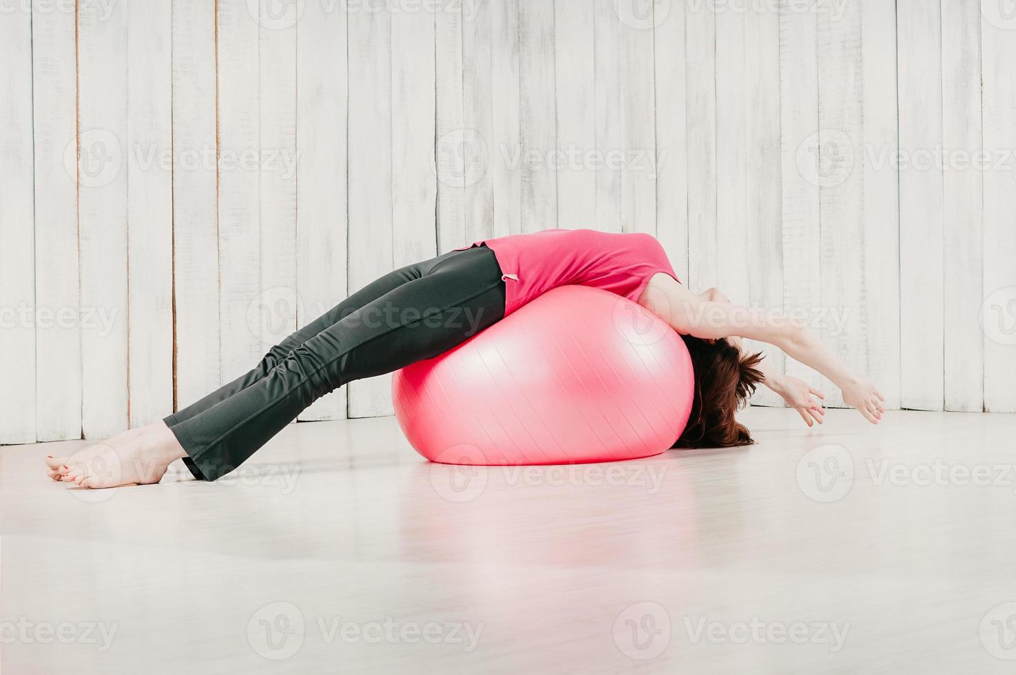Woman exercising on pink ball photo