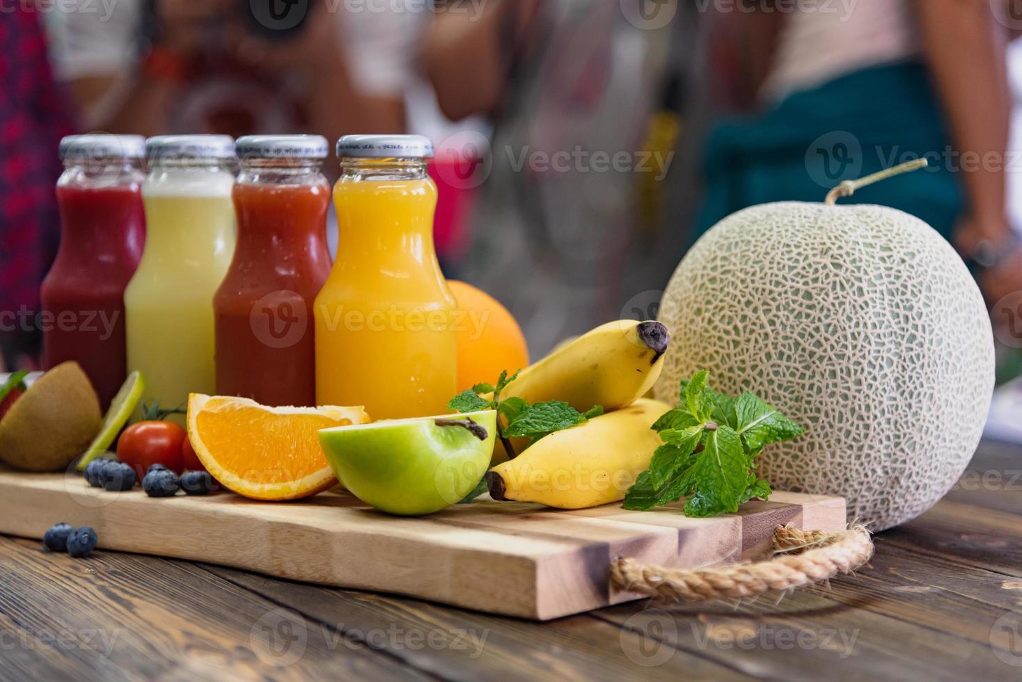 botella de jugo y frutas frescas en la mesa foto