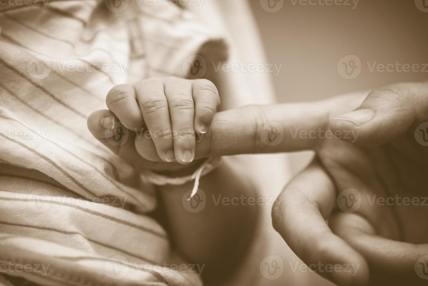 Bebé sosteniendo los dedos de la madre en concepto de amor y familia foto