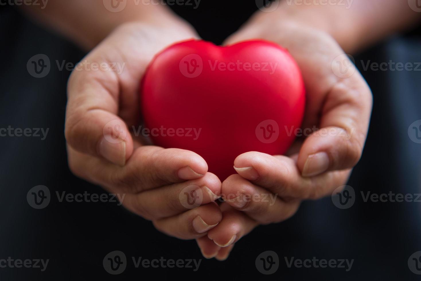 Cerrar las manos dando corazón rojo como donante de corazón foto