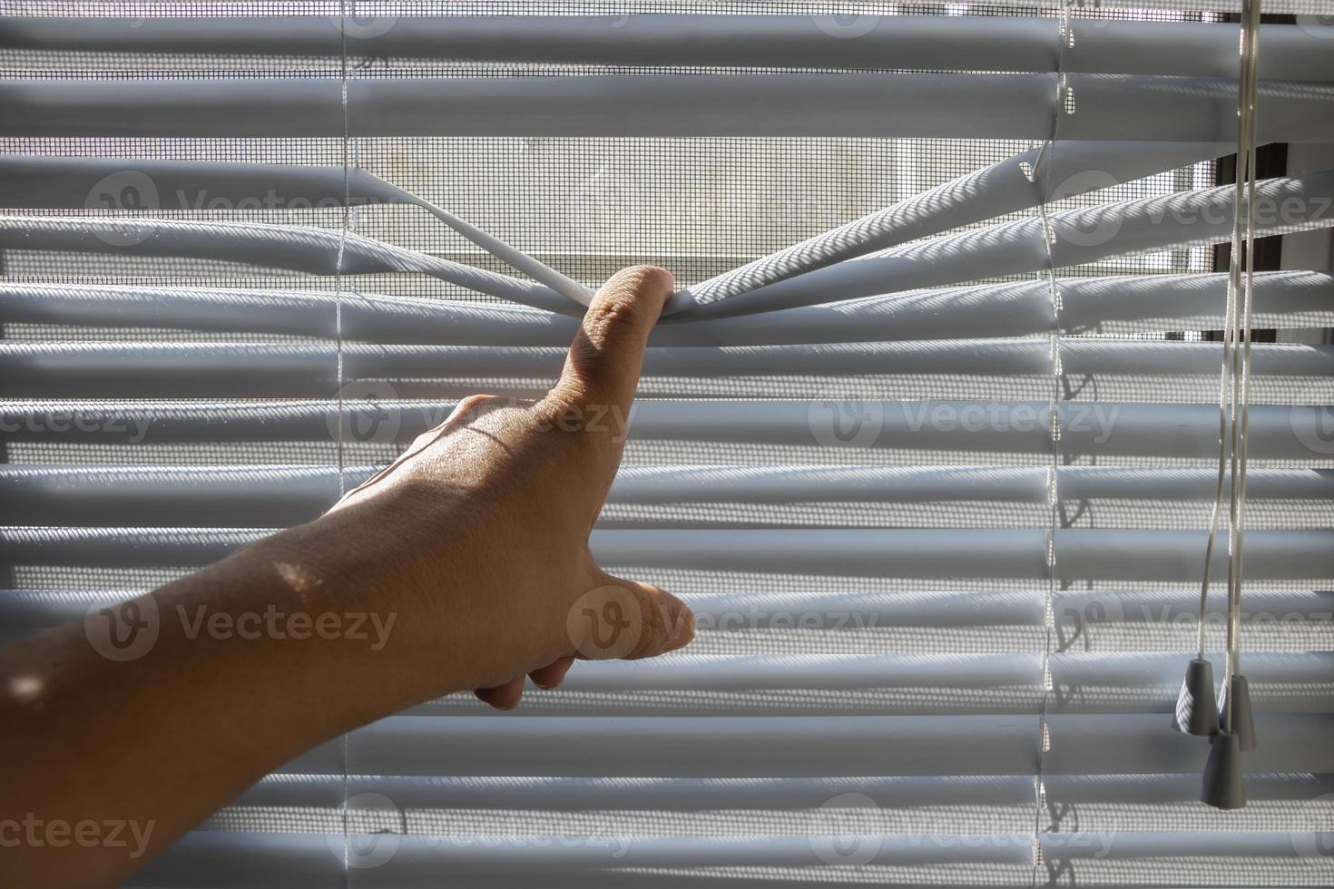 The fingers stretched the window blinds looking outside. photo