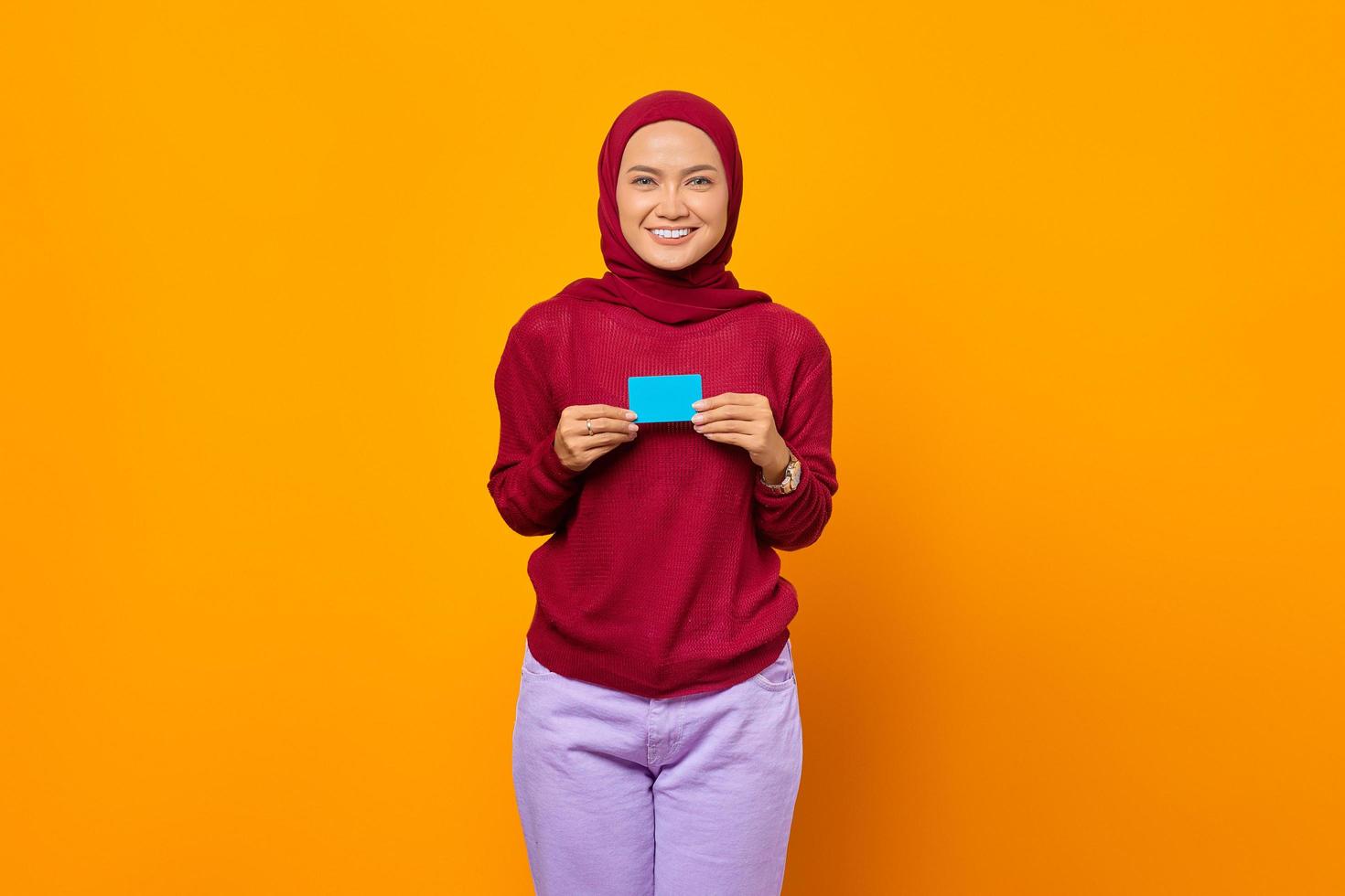 Smiling Asian woman holding blank card over yellow background photo