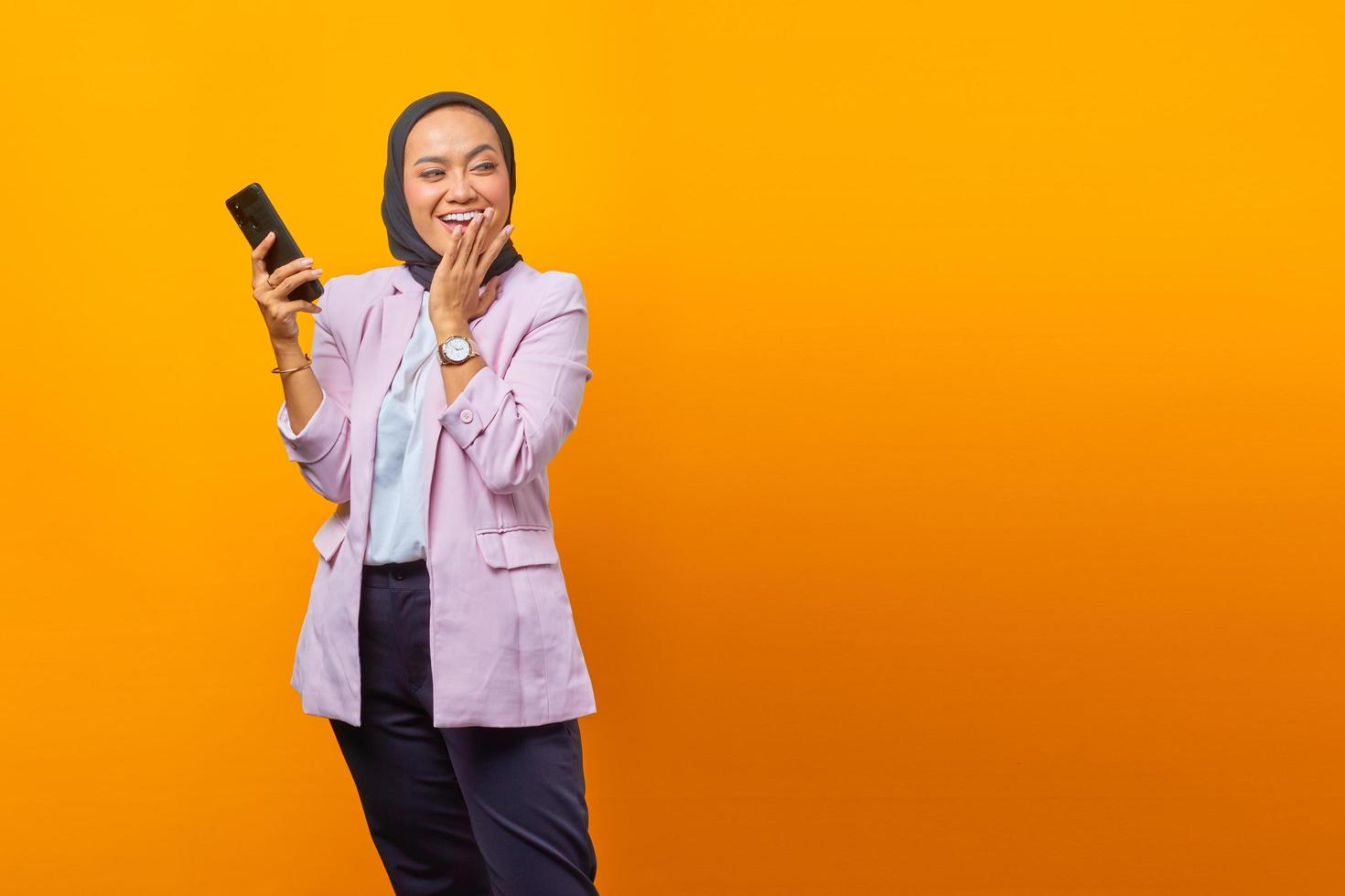 Sorprendido mujer asiática mediante teléfono móvil con la boca abierta foto