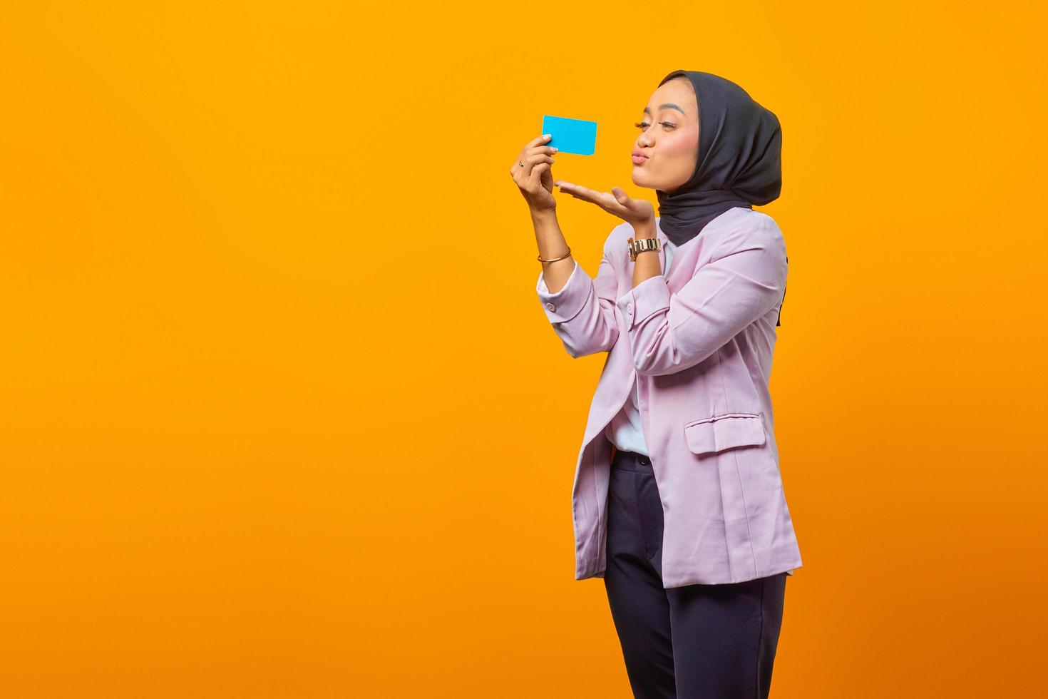 Cheerful Asian woman sending kiss and holding credit card photo