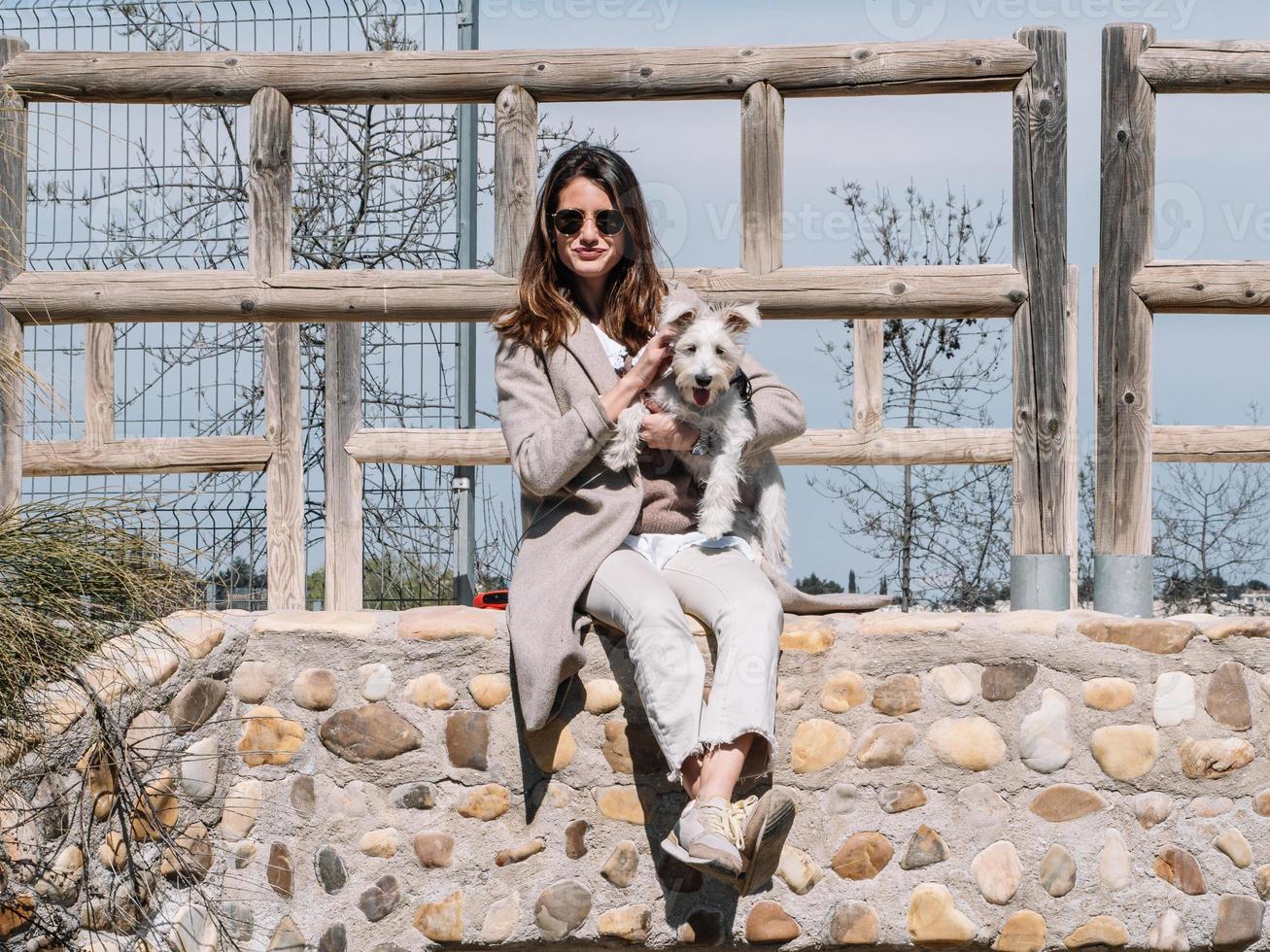 mujer joven sentada sobre un perro schauzer de piedra, foto