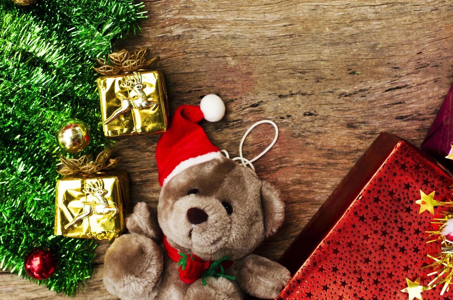 Oso de peluche con decoración navideña sobre fondos de madera arriba foto