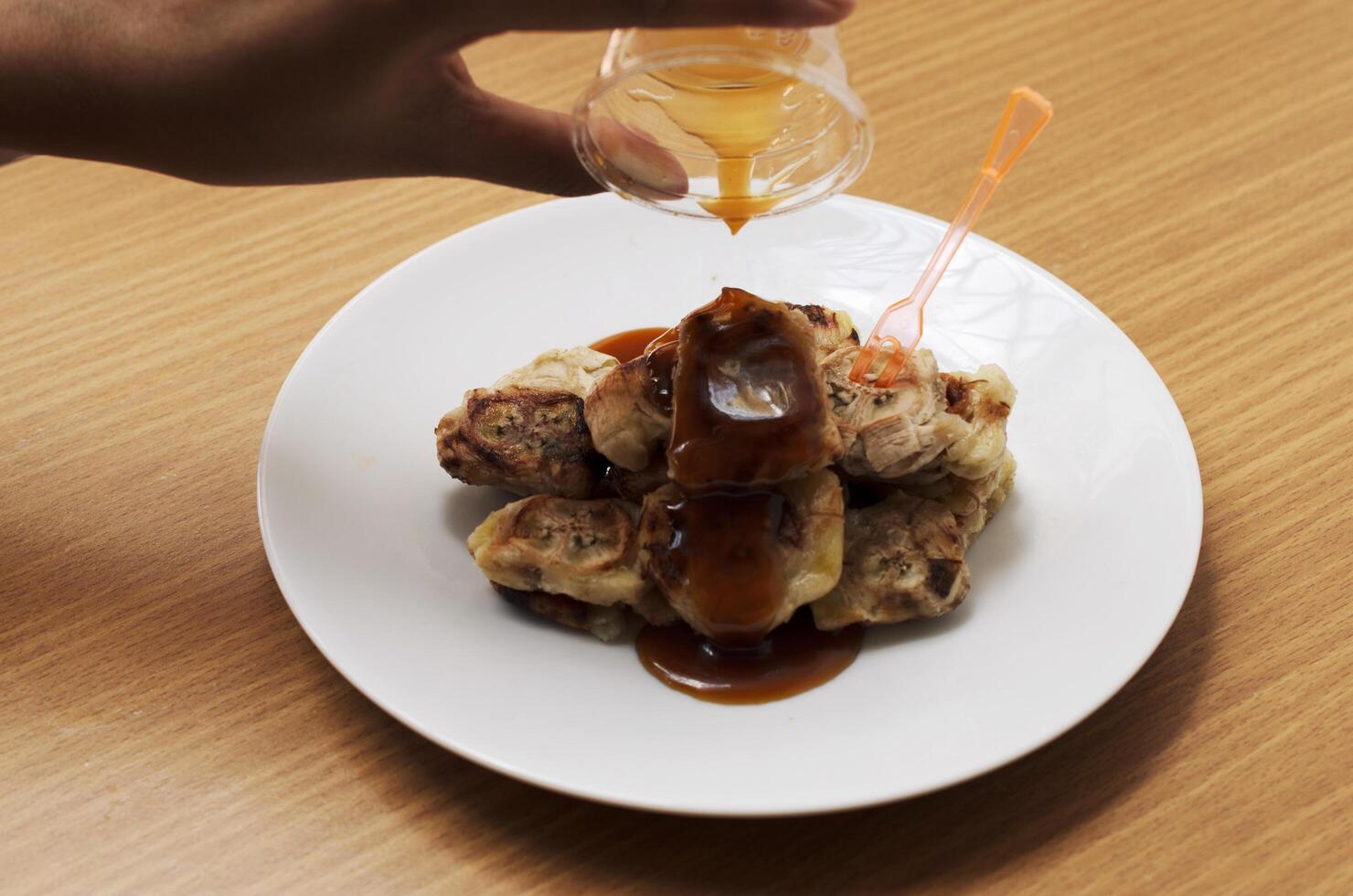 Pouring sweet sauce on grilled banana to eat photo