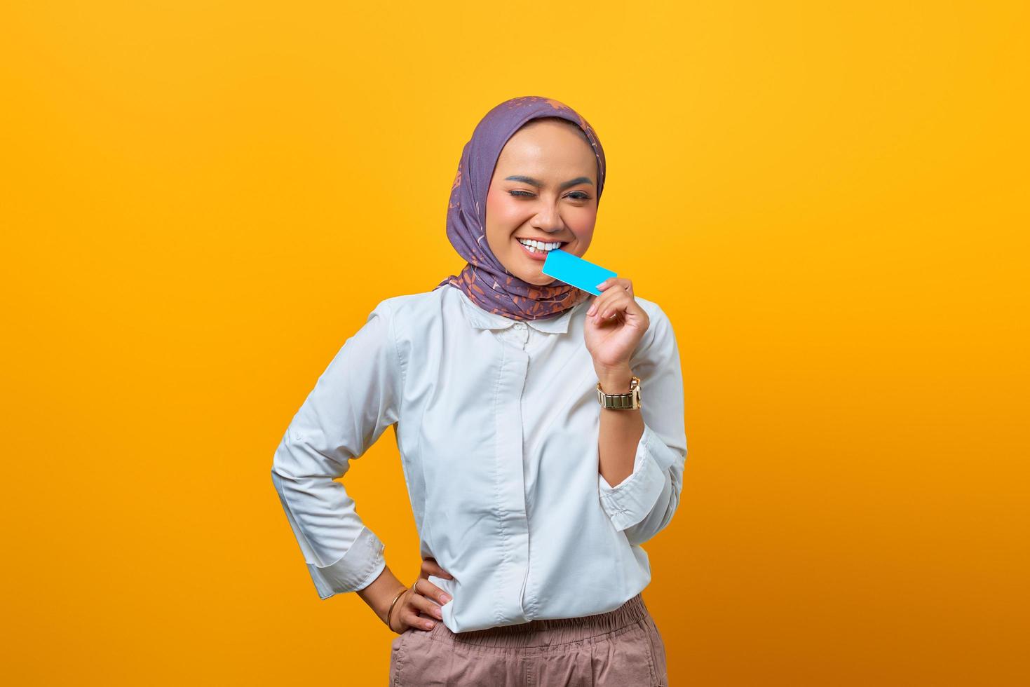 Beautiful Asian woman biting blank card and looking at camera photo