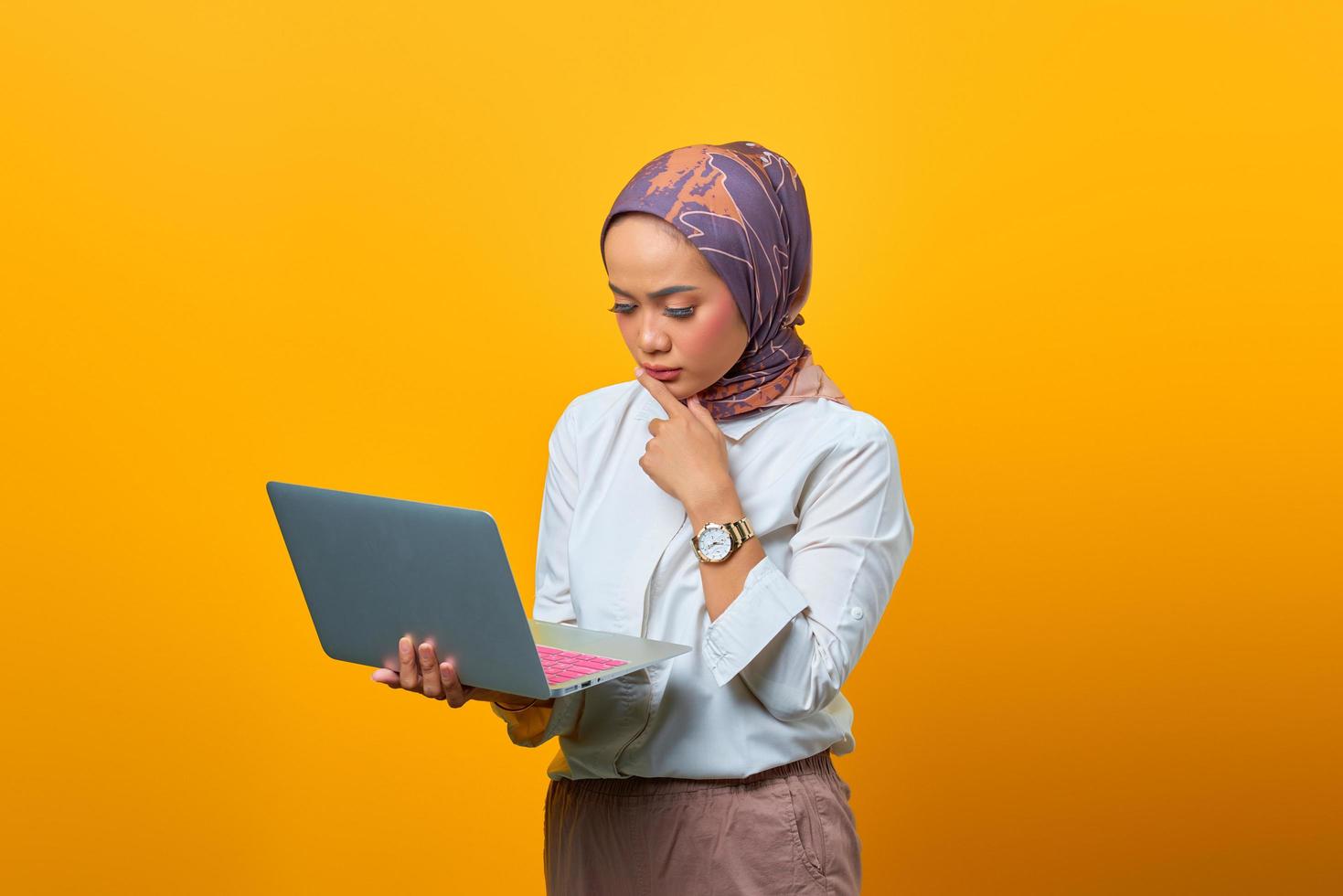 Beautiful Asian woman holding laptop with serious expression photo