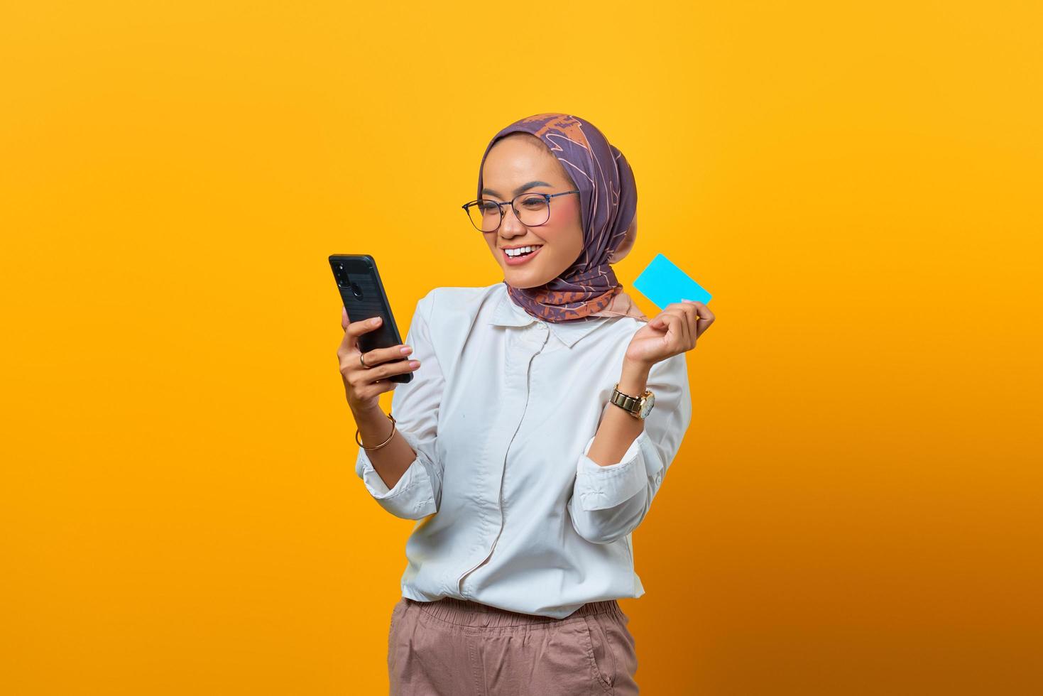 Cheerful Asian woman holding smartphone and showing blank card photo