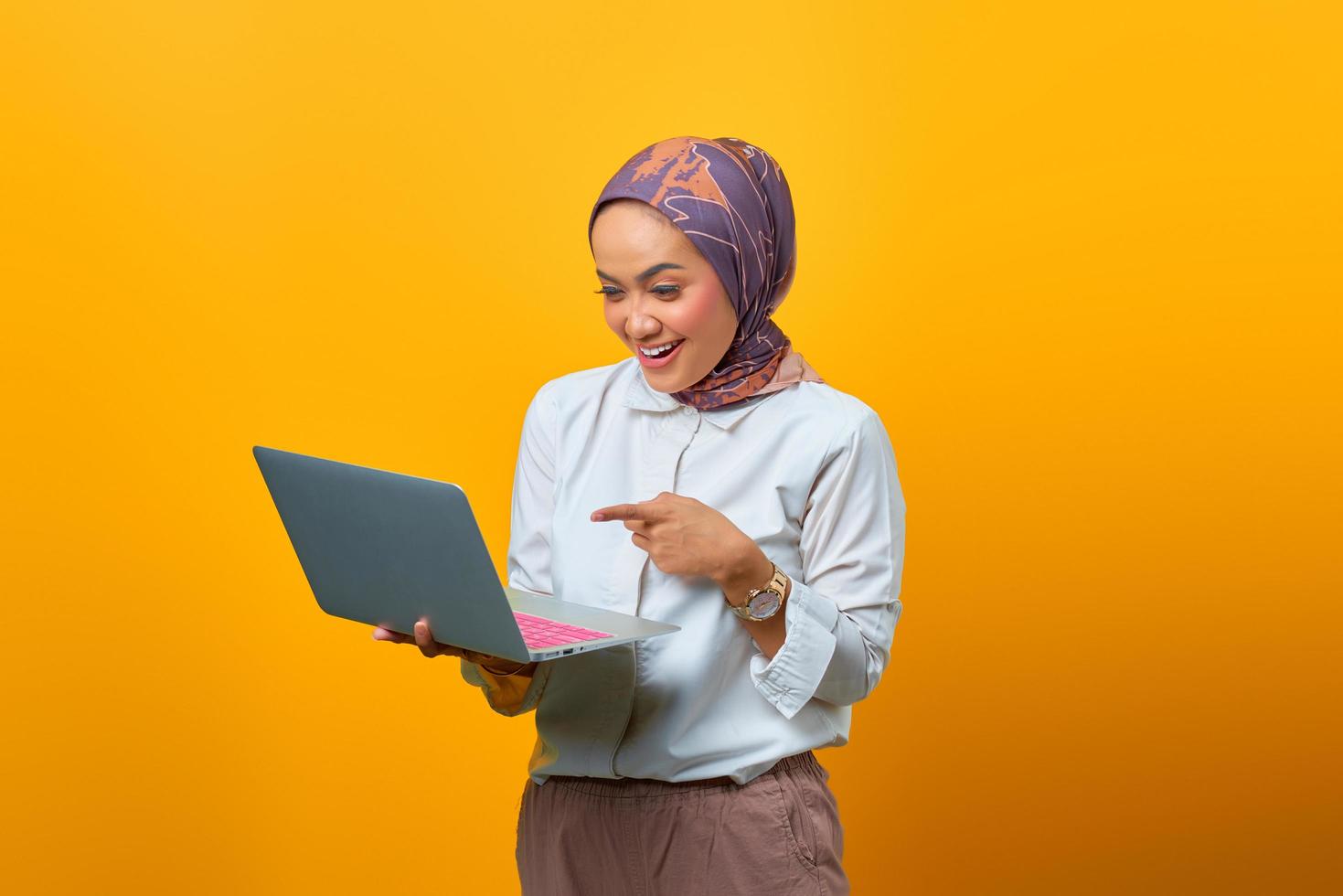 Retrato de mujer asiática sonriente sosteniendo portátil sobre fondo amarillo foto